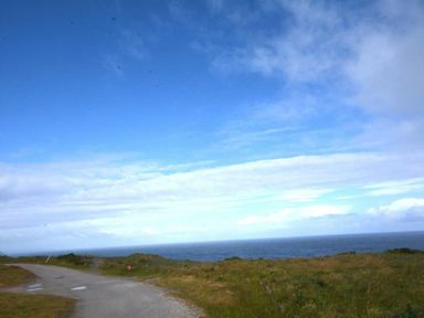 a coastal scene with a road leading to the ocean at Perran Sands - Holiday Accommodation 20514, Perranporth
