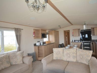 a living room with a sofa, kitchen area, and dining setup at Perran Sands - Holiday Accommodation 20514, Perranporth