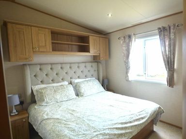 a bedroom with a double bed and wooden cabinets above at Perran Sands - Holiday Accommodation 20514, Perranporth