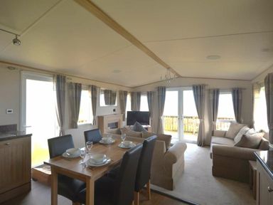 a dining area with a table set for meals and a living space with sofas at Perran Sands - Holiday Accommodation 20514, Perranporth