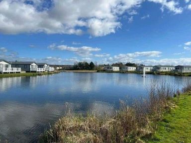 a lake surrounded by holiday homes at Lakeland Leisure Park - Holiday Accommodation 20788 in Flookburgh