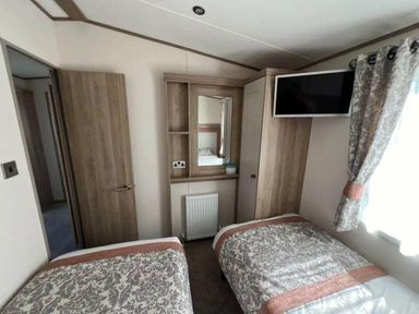 a bedroom with two single beds and a mirror at Lakeland Leisure Park - Holiday Accommodation 20788, Flookburgh