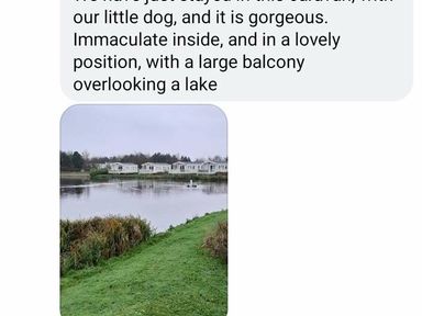 a lake view with a grassy area and holiday accommodations in the background at Lakeland Leisure Park - Holiday Accommodation 20788 Flookburgh