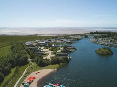 aerial view of a holiday park with buildings, a lake, and outdoor activity area at Lakeland Leisure Park - Holiday Accommodation 20788, Flookburgh
