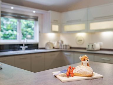 a kitchen with a loaf of bread and small tomatoes on a cutting board at Kelling Heath Holiday Park - Holiday Accommodation 20952 Weybourne