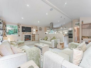 a living room with sofas and a kitchen area at Kelling Heath Holiday Park - Holiday Accommodation 20952 in Weybourne