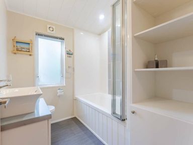 a bathroom with a bathtub, sink, and shelves at Kelling Heath Holiday Park - Holiday Accommodation 20952 in Weybourne