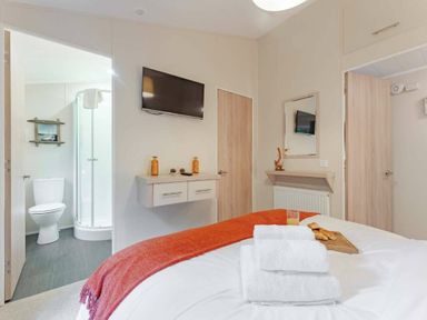 a bedroom featuring a bed with towels and a tray on it at Kelling Heath Holiday Park - Holiday Accommodation 20952 in Weybourne