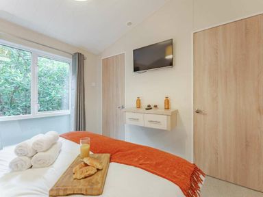 a bedroom with a bed, television, and two doors at Kelling Heath Holiday Park - Holiday Accommodation 20952, Weybourne