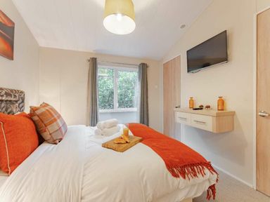 a bedroom with a bed, television, and window at Kelling Heath Holiday Park - Holiday Accommodation 20952 in Weybourne