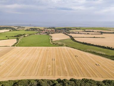 a landscape with fields and a village near the coast at Kelling Heath Holiday Park - Holiday Accommodation 20952 Weybourne