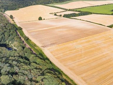 an aerial view of agricultural fields with harvested crops and forested areas at Kelling Heath Holiday Park - Holiday Accommodation 20952, Weybourne