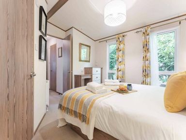 a bedroom with a bed, towels, and a tray of fruit at Kelling Heath Holiday Park - Holiday Accommodation 20958 Weybourne