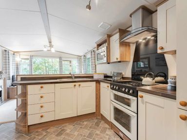 a kitchen with cabinets, countertop, stove, and sink at Kelling Heath Holiday Park - Holiday Accommodation 20958 in Weybourne