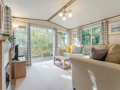 a living room with a sofa, coffee table, and large windows at Kelling Heath Holiday Park - Holiday Accommodation 20958 in Weybourne