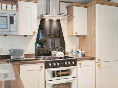 a kitchen with a stove and microwave at Kelling Heath Holiday Park - Holiday Accommodation 20958 in Weybourne