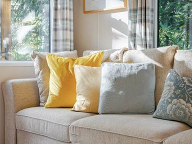 a sofa with various colored cushions at Kelling Heath Holiday Park - Holiday Accommodation 20958, Weybourne