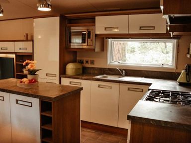 a kitchen with modern cabinetry, a sink, a microwave, and a cooking area at Kelling Heath Holiday Park - Holiday Accommodation 21026, Kelling Heath