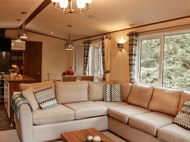 a living room with a sectional sofa and dining area at Kelling Heath Holiday Park - Holiday Accommodation 21026 Kelling Heath