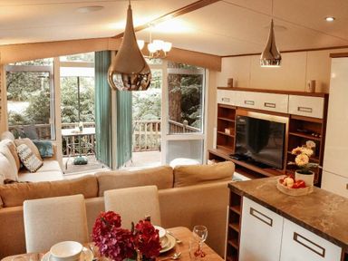 a living room with a sofa, dining table, and television at Kelling Heath Holiday Park - Holiday Accommodation 21026, Kelling Heath