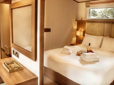 a bedroom with a bed and mirror with towels and champagne at Kelling Heath Holiday Park - Holiday Accommodation 21026, Kelling Heath