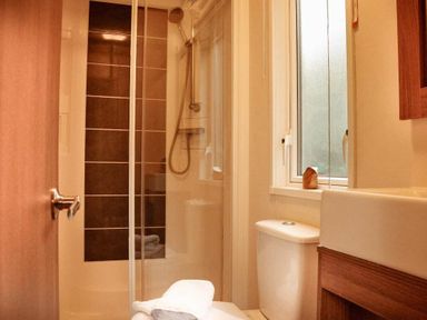 a bathroom featuring a shower with glass door and a toilet at Kelling Heath Holiday Park - Holiday Accommodation 21026, Kelling Heath