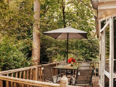 a deck area with a table and chairs under an umbrella at Kelling Heath Holiday Park - Holiday Accommodation 21026, Kelling Heath