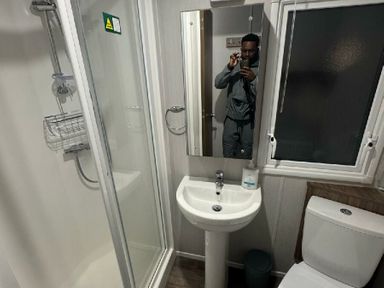 a bathroom with a shower, sink, mirror, and toilet at Butlins Skegness - Holiday Accommodation 21028 Skegness