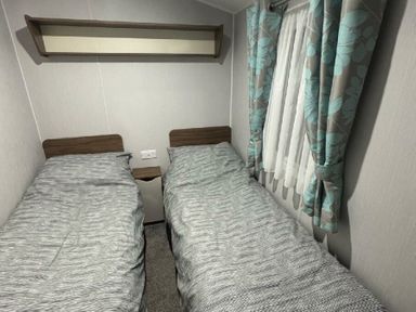 a small bedroom with two single beds and a shelf above at Butlins Skegness - Holiday Accommodation 21028, Skegness