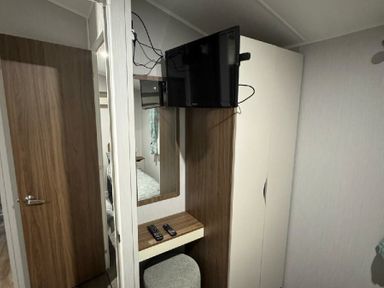 a room with a mounted TV, a small table, and a mirror at Butlins Skegness - Holiday Accommodation 21028 in Skegness