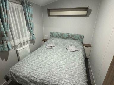 a bedroom with a double bed and floral-patterned bedding at Butlins Skegness - Holiday Accommodation 21028 in Skegness