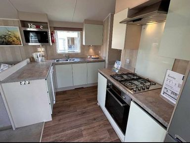 a kitchen with cabinets, a stove, and a sink at Perran Sands - Holiday Accommodation 21088 in Perranporth