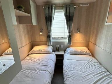 a bedroom with two single beds and a nightstand at Perran Sands - Holiday Accommodation 21088, Perranporth