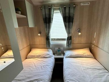 a bedroom with two single beds and soft lighting at Perran Sands - Holiday Accommodation 21088, Perranporth