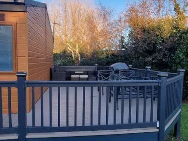 a deck with outdoor seating and a grill at Presthaven Beach Resort - Holiday Accommodation 21358 Prestatyn