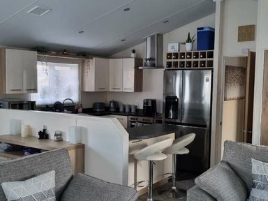 a kitchen area with modern appliances and seating at Presthaven Beach Resort - Holiday Accommodation 21358 in Prestatyn