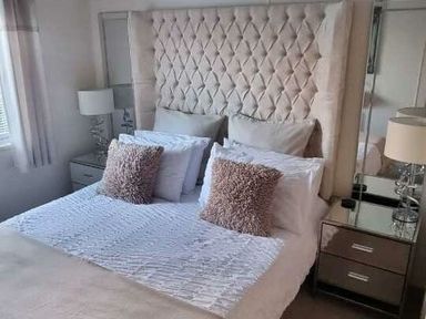 a bedroom with a large tufted headboard and decorative pillows at Presthaven Beach Resort - Holiday Accommodation 21358 in Prestatyn