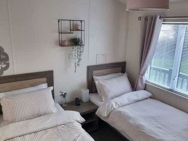 a twin bedroom with two beds and a nightstand at Presthaven Beach Resort - Holiday Accommodation 21358 in Prestatyn
