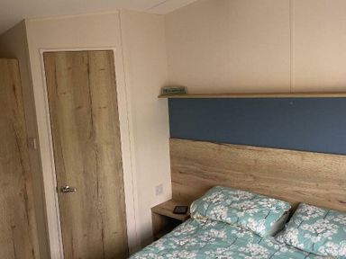 a bedroom with a bed and bedside table at Greenacres Holiday Park - Holiday Accommodation 21467 in Morfa Bychan