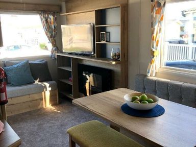 a living room with a television, seating area, and table at Greenacres Holiday Park - Holiday Accommodation 21467 Morfa Bychan