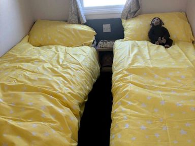 a room with two beds covered in yellow star-patterned bedding at Greenacres Holiday Park - Holiday Accommodation 21467, Morfa Bychan