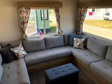 a seating area with a sectional couch and a small ottoman at Greenacres Holiday Park - Holiday Accommodation 21467, Morfa Bychan