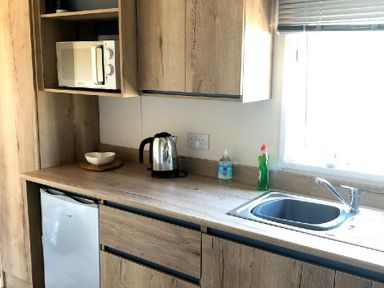 a kitchen with a microwave, kettle, sink, and fridge at Greenacres Holiday Park - Holiday Accommodation 21467, Morfa Bychan