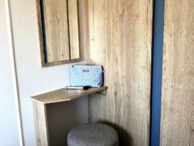 a vanity area with a mirror, wooden shelf, and a stool at Greenacres Holiday Park - Holiday Accommodation 21467 in Morfa Bychan