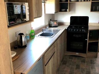 a kitchen with a sink, microwave, kettle, and oven at Greenacres Holiday Park - Holiday Accommodation 21467 Morfa Bychan