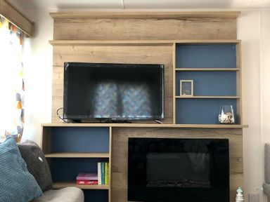 a wooden entertainment unit with a TV and shelves at Greenacres Holiday Park - Holiday Accommodation 21467 in Morfa Bychan