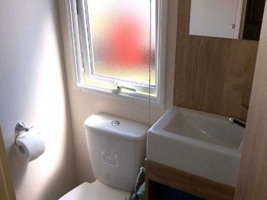 a bathroom with a toilet and sink near a frosted window at Greenacres Holiday Park - Holiday Accommodation 21467 Morfa Bychan