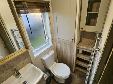 a bathroom with a toilet, sink, and storage shelves at Tattershall Lakes Country Park - Holiday Accommodation 21501 in Tattershall