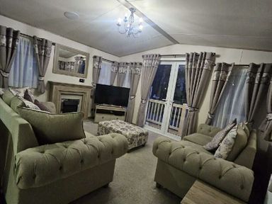 a living room with beige sofas, a television, and large windows at Tattershall Lakes Country Park - Holiday Accommodation 21501 in Tattershall