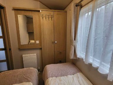 a bedroom with two single beds and a wooden wardrobe at Swanage Bay View - Holiday Accommodation 21567 in Swanage